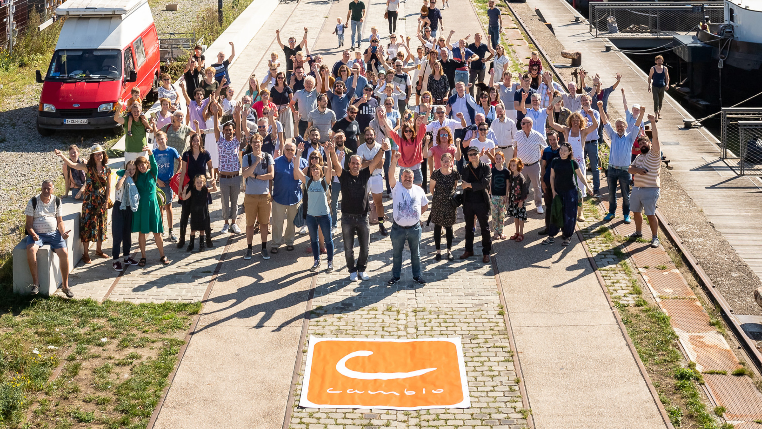 zonnige groepsfoto van bezoekers die aanwezig waren op het cambio deelfeest met voor hen het logo van cambio